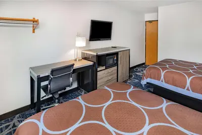a hotel room with a bed and a desk and a television at Super 8 by Wyndham Johnstown/Gloversville in Johnstown