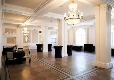 a large room with a chandelier and tables and chairs at The Queensbury Hotel in Glens Falls