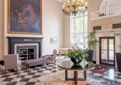 a living room with a fireplace and a chandelier at The Queensbury Hotel in Glens Falls