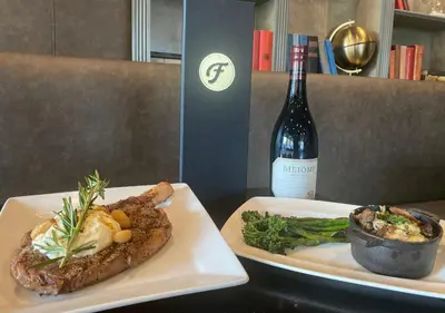 two plates of food and a bottle of wine at The Queensbury Hotel in Glens Falls