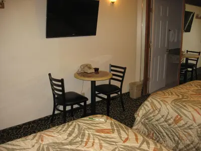 a hotel room with a table and chairs and a bed at Domino Inn in North Bergen