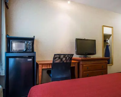a bedroom with a desk with a tv and a chair at Econo Lodge Glens Falls - Lake George in Glens Falls