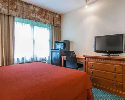 a hotel room with a bed and a flat screen tv at Econo Lodge Glens Falls - Lake George in Glens Falls
