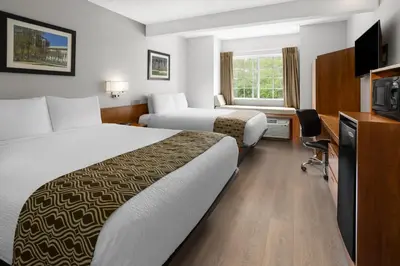a hotel room with two beds and a television at Microtel Inn by Wyndham - Albany Airport in Latham