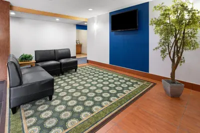 a waiting room with a couch and a tv at Microtel Inn by Wyndham - Albany Airport in Latham