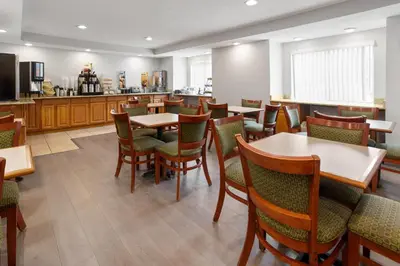 a restaurant with tables and chairs and a kitchen at Microtel Inn by Wyndham - Albany Airport in Latham