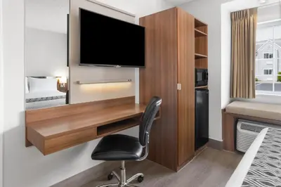 a room with a desk with a television and a chair at Microtel Inn by Wyndham - Albany Airport in Latham