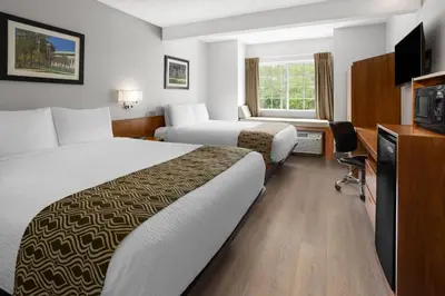 a hotel room with two beds and a television at Microtel Inn by Wyndham - Albany Airport in Latham