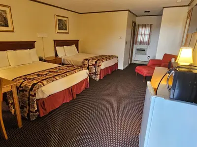 a hotel room with two beds and a television at Alpenhaus Motel in Queensbury