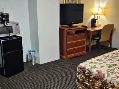 a hotel room with a bed and a desk with a television at Alpenhaus Motel in Queensbury