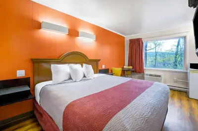 a bedroom with a large bed with an orange wall at Motel 6-Ilion, NY in Ilion