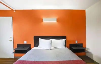a bed in a room with an orange wall at Motel 6-Ilion, NY in Ilion