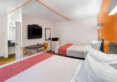 a hotel room with two beds and a table and a tv at Motel 6-Ilion, NY in Ilion
