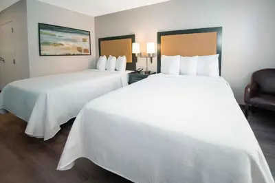 two beds in a hotel room with white sheets at Extended Stay America Suites - White Plains - Elmsford in Elmsford