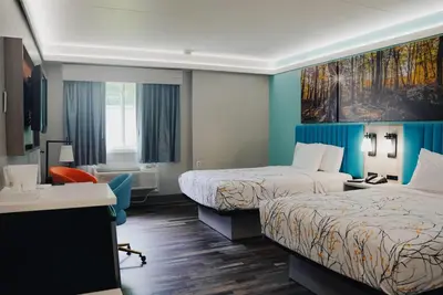 a hotel room with two beds and a desk at Days Inn by Wyndham Southington in Southington