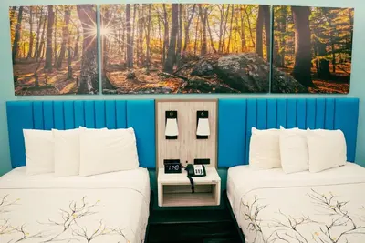 two beds in a room with blue walls at Days Inn by Wyndham Southington in Southington