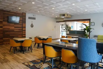 a dining room with tables and chairs and a tv at Days Inn by Wyndham Southington in Southington