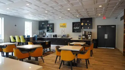 a restaurant with tables and chairs and a kitchen at Days Inn by Wyndham Southington in Southington