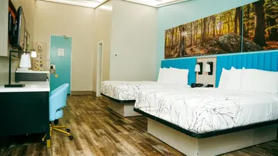 two beds in a room with blue walls and wooden floors at Days Inn by Wyndham Southington in Southington