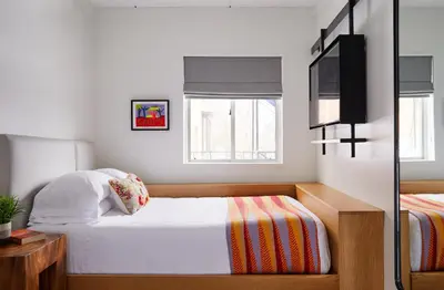 a small bedroom with a bed and a tv at Bluebird Spa City Motor Lodge in Saratoga Springs