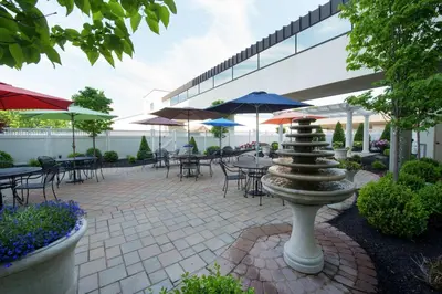 a patio with tables and chairs and umbrellas at DoubleTree by Hilton Binghamton in Binghamton