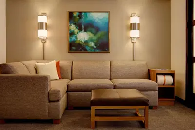 a living room with a couch and a painting at Hyatt Place Saratoga/Malta in Malta
