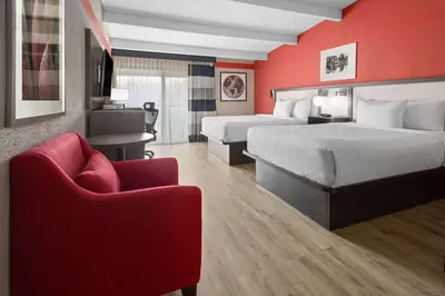 a hotel room with two beds and a red wall at Ramada by Wyndham Parsippany in Parsippany