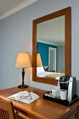 a bedroom with a bed and a desk with a mirror at Gideon Putnam Resort & Spa in Saratoga Springs