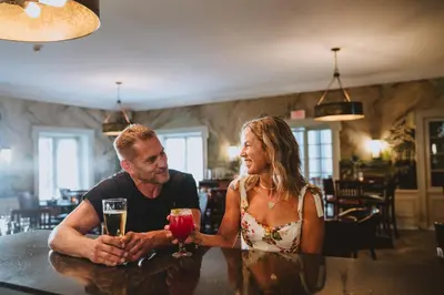 a man and a woman sitting at a bar with drinks at Gideon Putnam Resort & Spa in Saratoga Springs