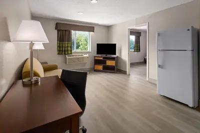 a living room with a white refrigerator and a table at Super 8 by Wyndham Latham - Albany Airport in Latham