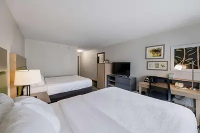 a hotel room with two beds and a desk at Country Inn & Suites by Radisson, Queensbury - Lake George , NY in Lake George