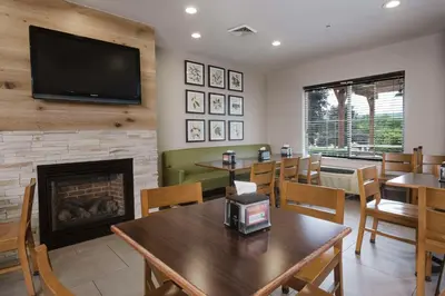 a restaurant with a fireplace and tables and chairs at Country Inn & Suites by Radisson, Queensbury - Lake George , NY in Lake George