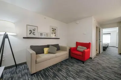 a living room with a couch and a red chair at Country Inn & Suites by Radisson, Queensbury - Lake George , NY in Lake George