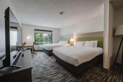 a hotel room with two beds and a television at Country Inn & Suites by Radisson, Queensbury - Lake George , NY in Lake George