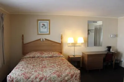 a hotel room with a bed and a desk and a mirror at Elm Motel in Westfield