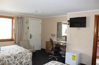 a hotel room with a bedroom with a desk and a bed at Elm Motel in Westfield