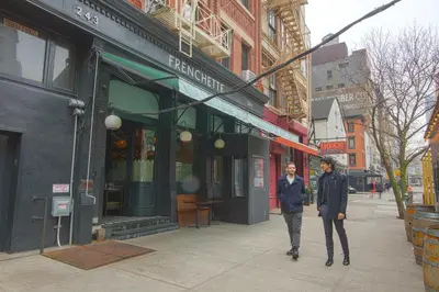 two men walking down a sidewalk in front of a store at The Frederick Hotel Tribeca in New York