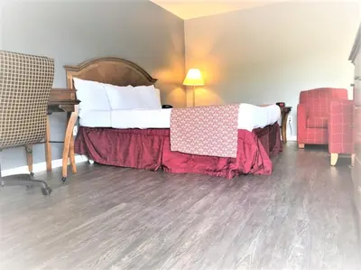 a bedroom with a bed with a red blanket on it at Countryside Inn Richmondville in Richmondville