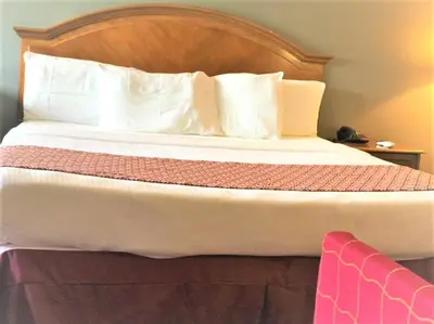 a large bed with a wooden headboard and white pillows at Countryside Inn Richmondville in Richmondville