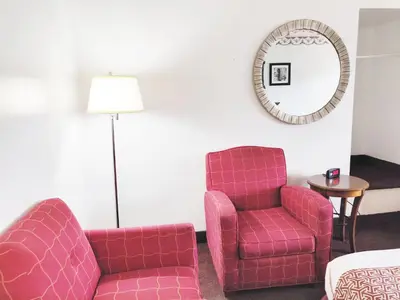 a living room with a pink chair and a mirror at Countryside Inn Richmondville in Richmondville
