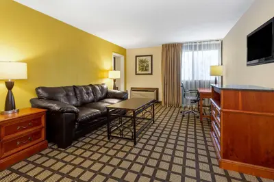 a living room with a leather couch and a table at Baymont by Wyndham Queensbury/Lake George in Queensbury