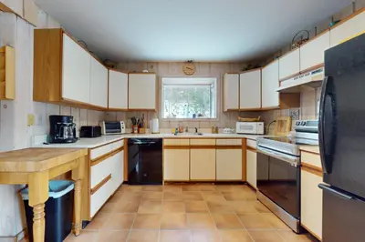 a kitchen with white cabinets and a table in it at West Dover Getaway in West Dover