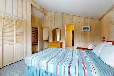 a bedroom with a bed and wooden walls at West Dover Getaway in West Dover