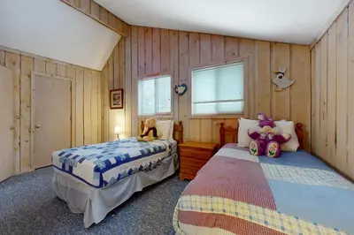 two beds in a bedroom with wooden walls and windows at West Dover Getaway in West Dover