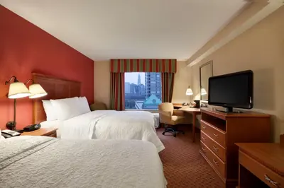 a hotel room with two beds and a flat screen tv at Hampton Inn & Suites East Hartford in East Hartford