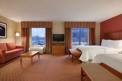 a hotel room with two beds and a television at Hampton Inn & Suites East Hartford in East Hartford