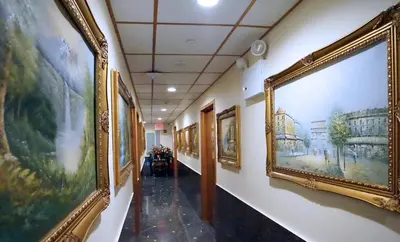 a hallway with a bunch of paintings on the walls at Paris Suites Hotel in Queens
