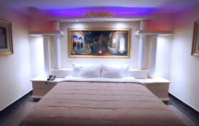 a bedroom with a large bed with a painting on the wall at Paris Suites Hotel in Queens