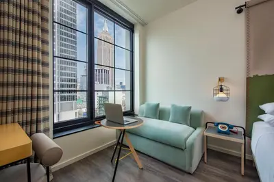 a hotel room with a couch and a laptop on a table at Moxy NYC Chelsea in New York