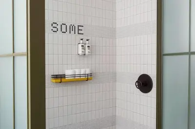 a white tiled shower with the words sue on the wall at Moxy NYC Chelsea in New York